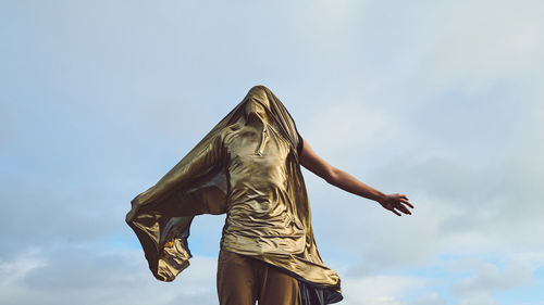 Low angle view of man covered with fabric against sky