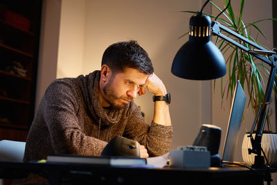 Side view of young woman using mobile phone at table