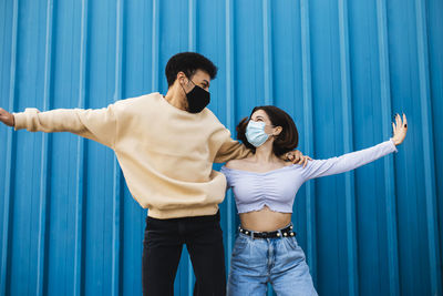 Young couple standing against blue curtain