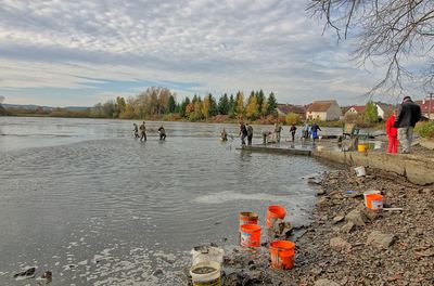 People on shore against sky