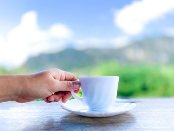 Hand holding coffee cup on table