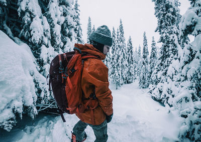 Rear view of man on snow covered tree during winter