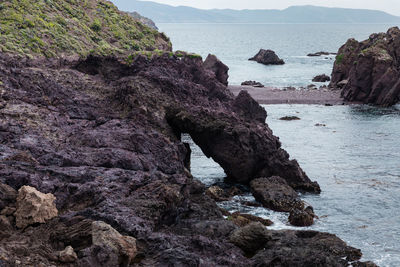 Rock formation on beach against sky