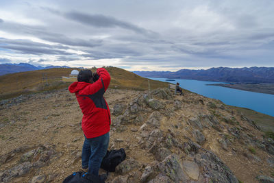 Rear view of man standing on mountain against sky