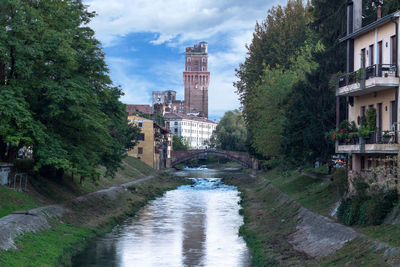 Arch bridge over river amidst buildings in city against sky