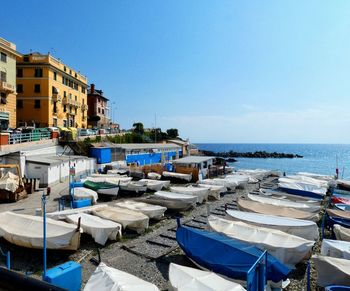 Boats moored on sea by buildings against clear blue sky