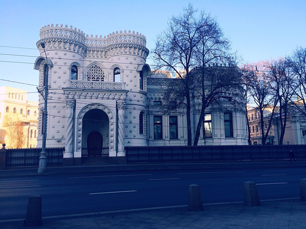 architecture, building exterior, built structure, clear sky, bare tree, facade, church, tree, arch, religion, place of worship, history, sky, city, blue, street, outdoors, entrance