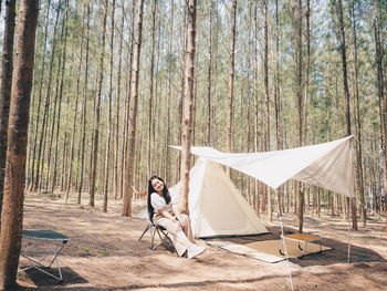 Happy asian teenage girl in front of camp tent. outdoor activity. 