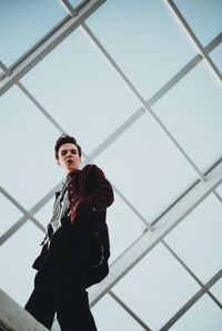 Low angle view of young man standing against railing