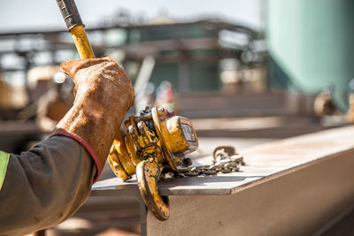 Cropped hand holding rusty machinery at construction site