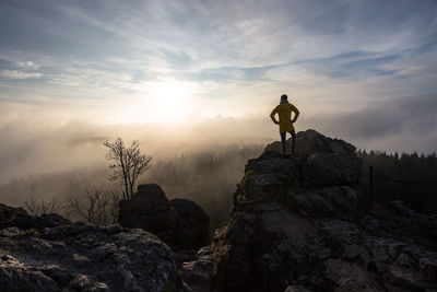 Man standing on rock against sky