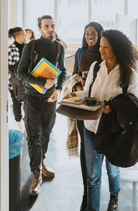 Smiling teacher walking with students in classroom at university