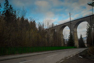 Road by arch bridge against sky