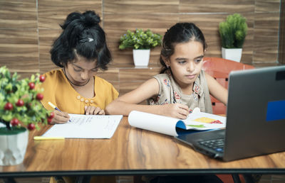 Cute girls studying with laptop in modern school during pandemic