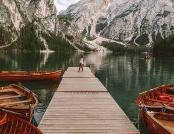 Woman standing on pier over lake against mountains