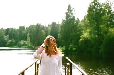 View of woman standing by railing against lake