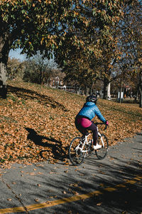 Person riding bicycle on street during autumn