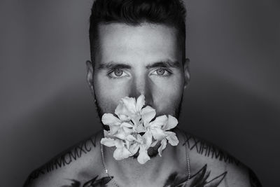 Close-up portrait of young man with flowers against wall