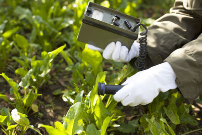 Scientist using equipment over plants at farm