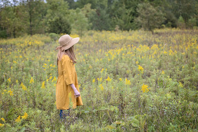 Young girl in yellow dress in a field of flowers