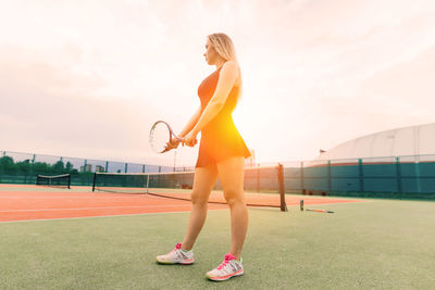 Full length of young woman exercising on field