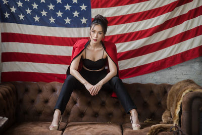 Full length of woman sitting against american flag