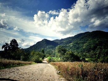 Road by mountains against sky