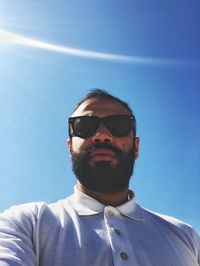 Portrait of young man wearing sunglasses against clear blue sky