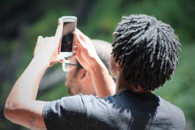 Rear view of woman photographing through smart phone