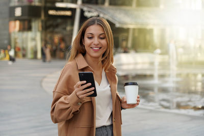 Entrepreneur young. busy woman. smartphone app. office worker outdoors. cappuccino coffee cup. 