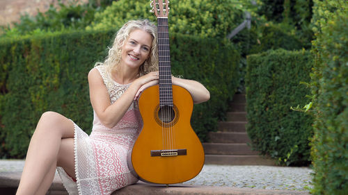 Portrait of a smiling young woman playing guitar