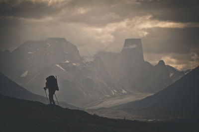 Silhouette of backpacker hiking through rugged mountain landscape