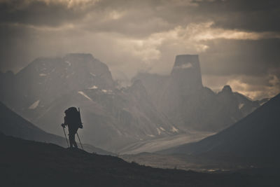 Rear view of man standing on mountain against sky