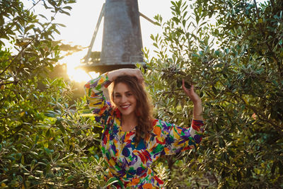 Smiling young woman standing by plants