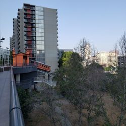 Train against buildings in city against clear sky