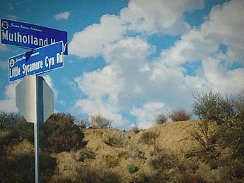 Low angle view of road sign against blue sky