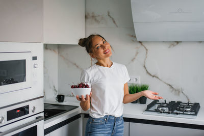 Happy nutritionist woman holds a fresh cherry berry in a plate in her hand