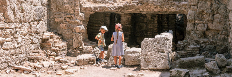 Kids sibling girl and boy travelers travel and explore the ancient excavations of the ruins