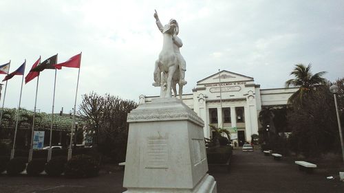 Statue in city against sky