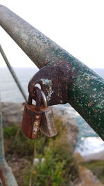 Close-up of padlocks on railing against sky