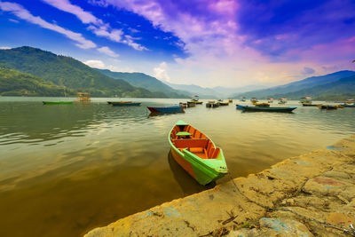 Boat moored on lake against sky