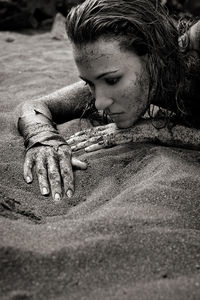 Close-up of muddy woman lying on sand at beach