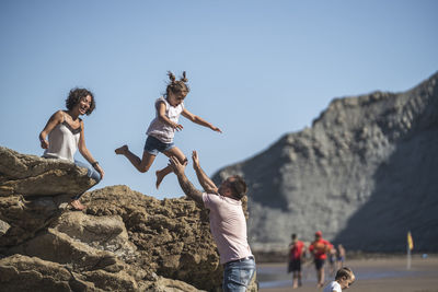 People jumping on rock against mountain