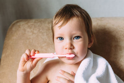 Cute child in big white towel. she brushes his teeth with toothbrush.