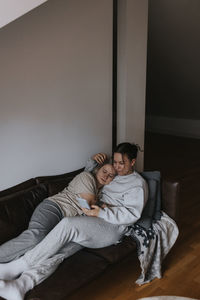 Female couple hugging together on sofa and looking at cell phone