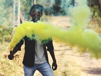 Young man holding distress flare on field