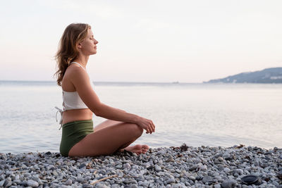 Vacation. health concept. beautiful young woman in swimsuit meditating on the beach