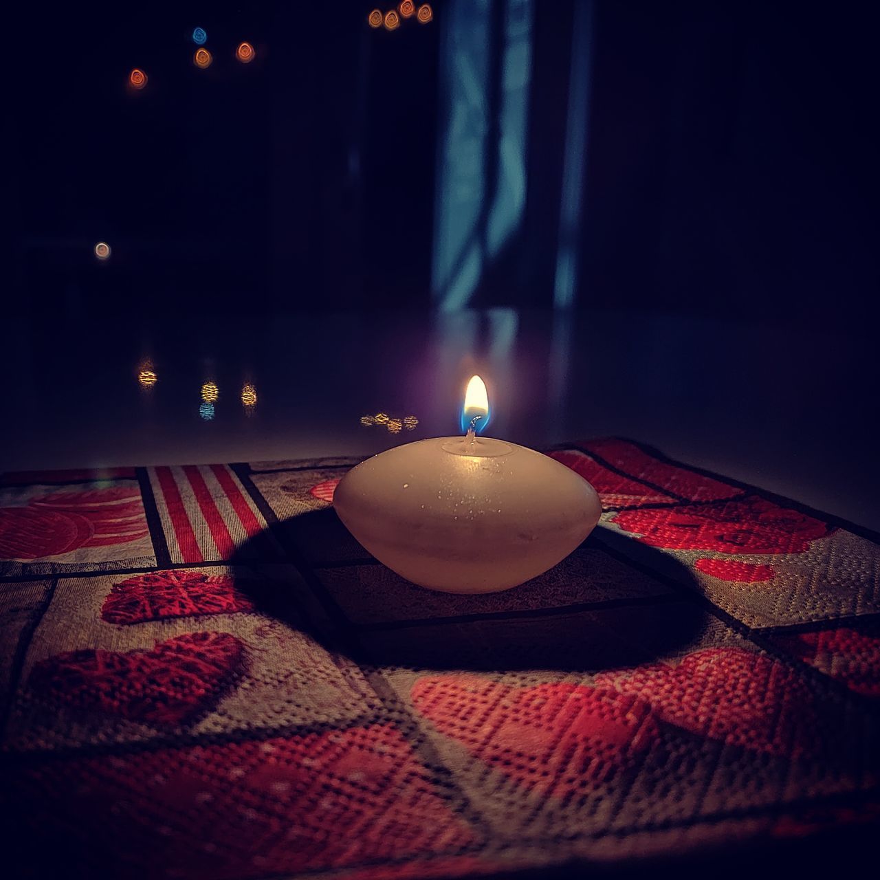 CLOSE-UP OF ILLUMINATED CANDLE ON TABLE