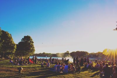 People relaxing at park against sky during sunset