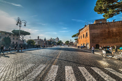 City street by buildings in town against sky